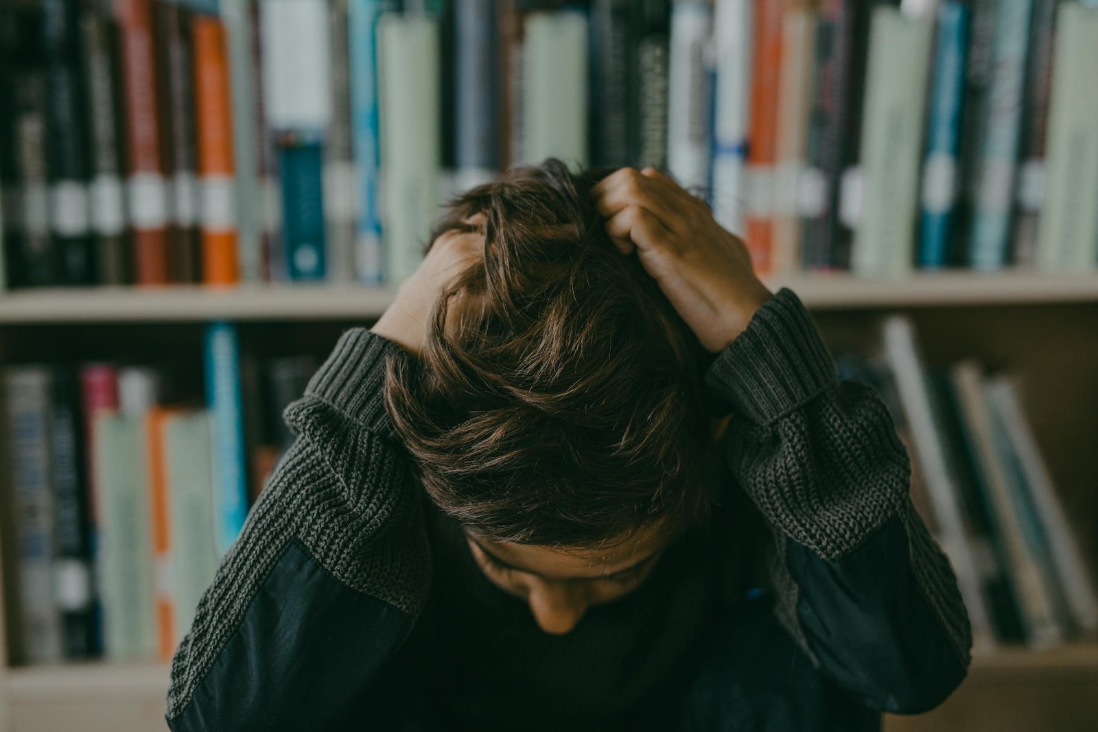 Women's Mental load A child appears stressed and frustrated while seated in a library, holding their head.